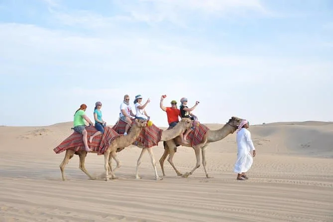 Camel riding at sunrise in Dubai desert with golden dunes