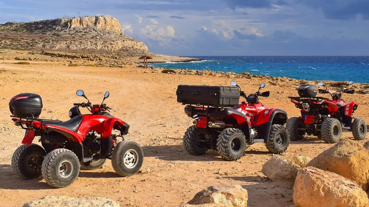 Tourist resting with water bottle in shade after dune buggy ride in Dubai summer heat